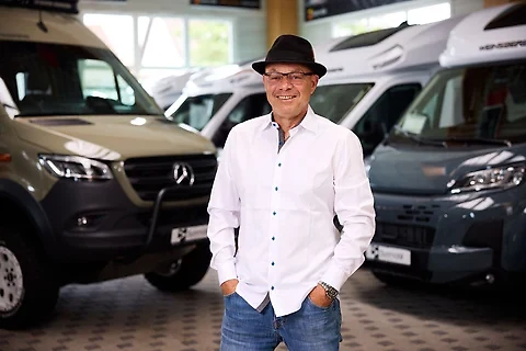 Mitarbeiter mit Hut zwischen den Fahrzeugen der Ausstellung