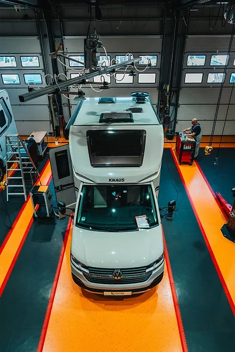 Blick von oben auf ein KNAUS-Wohnmobil in der Werkstatt mit Absauganlage über dem Dach