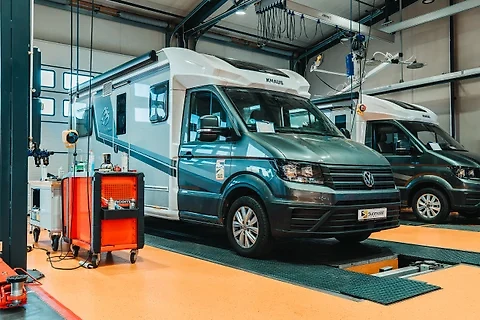 KNAUS-Wohnmobil auf der Hebebühne in der Werkstatthalle, daneben ein Werkzeugwagen