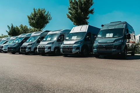 Reihe aktueller KNAUS-Camper-Vans der Mietflotte auf dem Hof